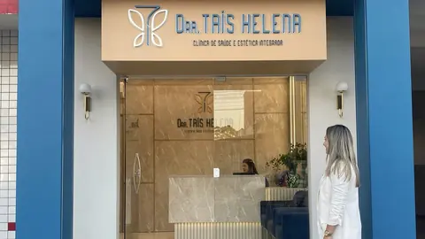 Fachada azul da clínica com o letreiro Dra. Taís Helena e a porta de vidro