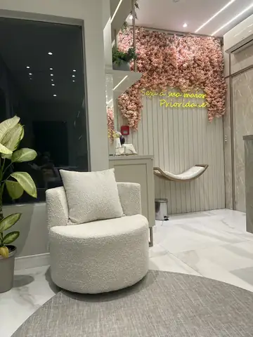 Recepção da clínica com poltrona clara e parede de flores
