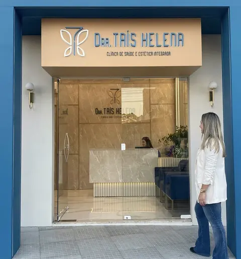 Entrada da clínica: porta de vidro com a recepção e o letreiro ao fundo